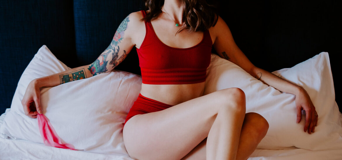 Rae Kennedy wears red lingerie on her bed