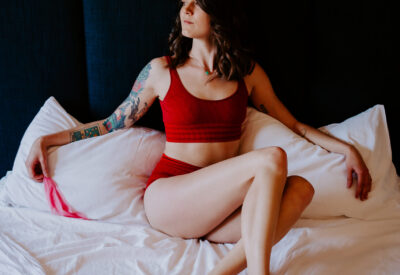 Rae Kennedy wears red lingerie on her bed