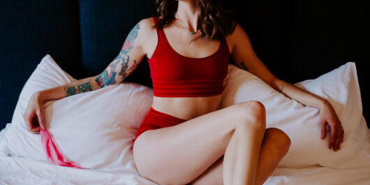 Rae Kennedy wears red lingerie on her bed