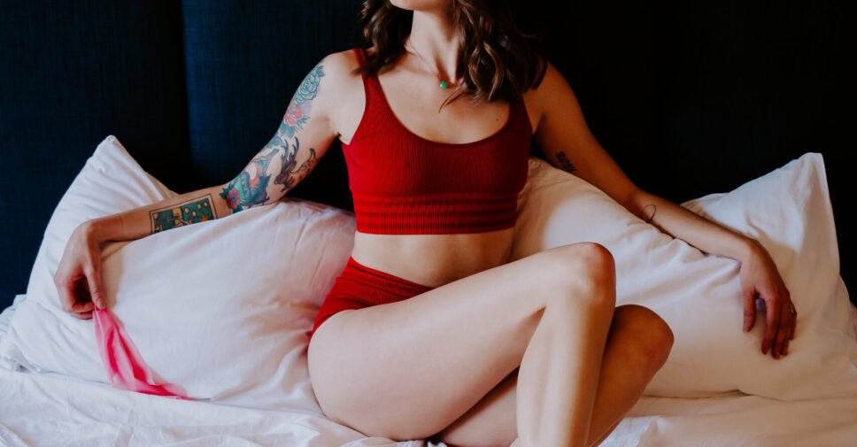 Rae Kennedy wears red lingerie on her bed