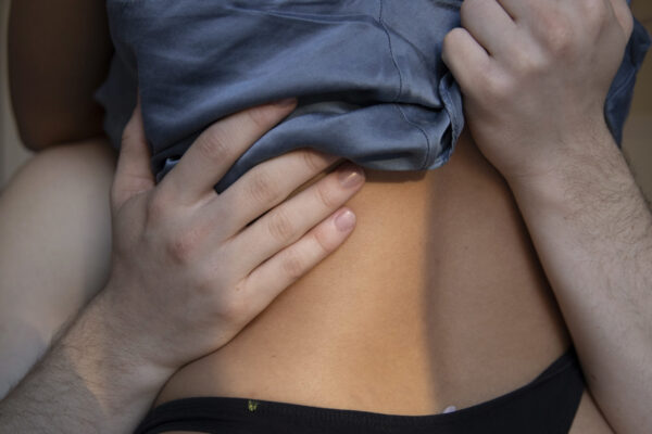 couple embracing each other with the man's hands on the woman's back pushing up her shirt